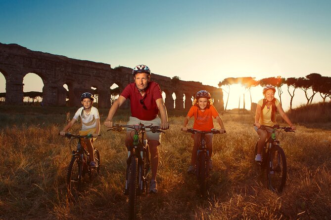 Cyclists on the basalt of the Appian Way under Roman aqueducts at sunset